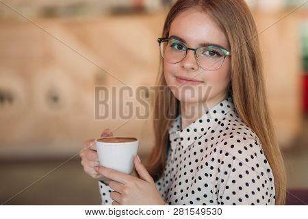 Blond Girl With Glasses In Polka-dot Shirt Grinking Coffee