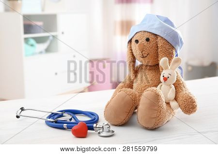 Composition With Toy Bunnies, Stethoscope And Heart On Table Indoors, Space For Text. Children's Doc