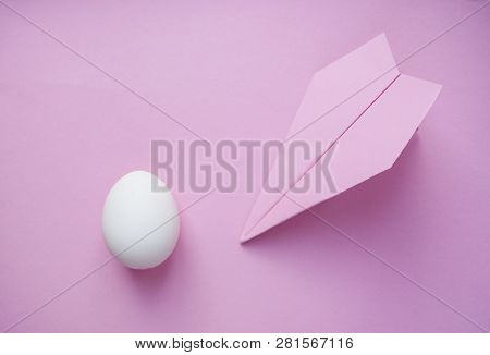 A White Single Egg On Pink Background With Paper Plane And Copyspace. Travel Concept.