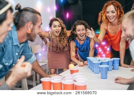 Group Of Happy Friends Playing Beer Pong In Pub Cocktail Bar - Young Millennials People Having Fun D
