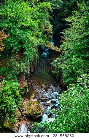 Wooden Bridge Over A Mountain River. Eastern Abkhazia. Near The Town Of Tkvarcheli. The Kambarka Dis