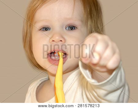 Little Baby Girl Dabbles And Has Fun While Learning To Brush Her First Teeth. The Child Shows The Fi