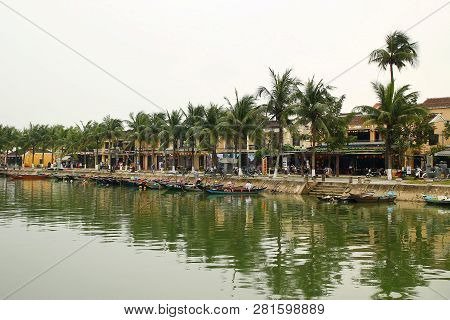 Hoi An, Vietnam - February 12, 2018: View On The Thu Bon River With Traditional Wooden Boats And Emb