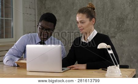 Two Entrepreneurs Sitting Together Working In An Office Desk Putting Notes To Notebook