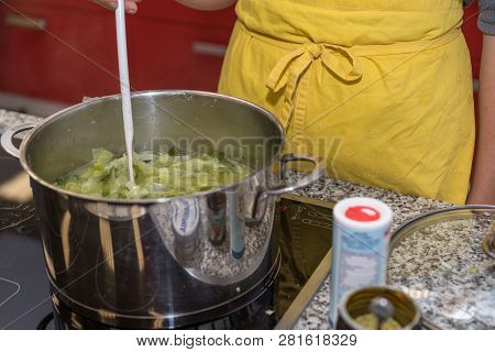 Cook Stirs With Wooden Spoon In Saucepan - Close-up