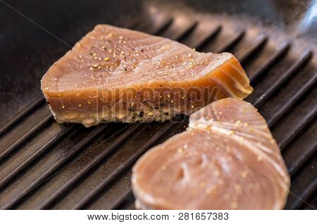 Close Up Of Chargrilled Tuna Steaks Cooking In A Griddle Pan With Seasoning