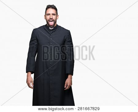 Young Christian priest over isolated background sticking tongue out happy with funny expression. Emotion concept.