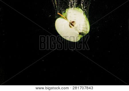 Half Of Apple Falls In Water On Black Background