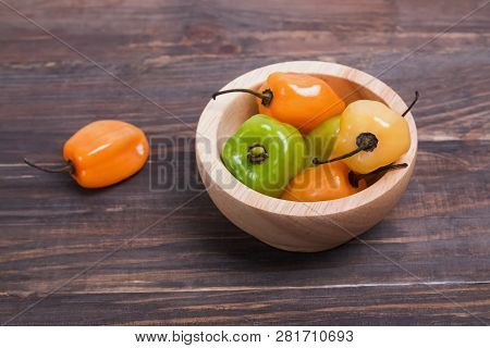 Fresh Spicy Habanero Peppers Of Different Colors In A Small Wooden Bowl