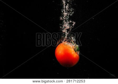 Sparkling Red Tomato Falls In Water And Splashes It
