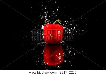 Sparkling Water Falls On Delicious Red Pepper Which Stands On Black Table