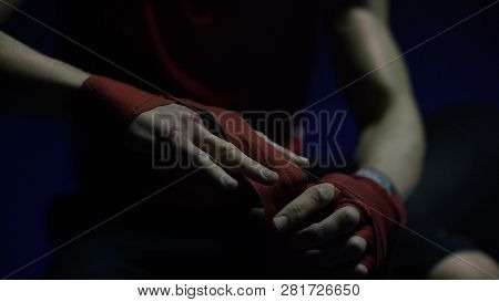 Close-up Of Boxer's Hand. Close-up Boxer Ties Injured Hands With Red Ribbon In Dark Locker Room, Pre