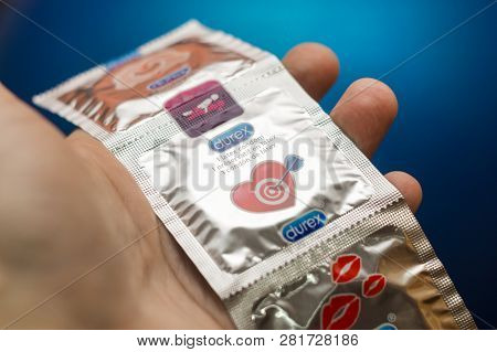 Tyumen, Russia - February 01, 2019: Durex Condom In Hand On Blue Background Close-up. Used To Preven
