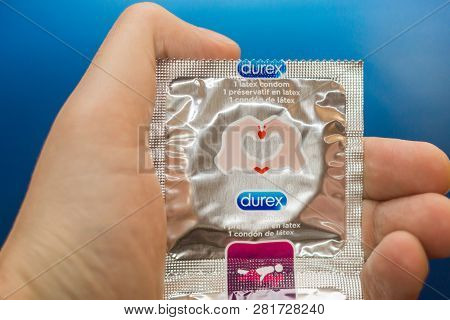 Tyumen, Russia - February 01, 2019: Durex Condom In Hand On Blue Background Close-up. Used To Preven