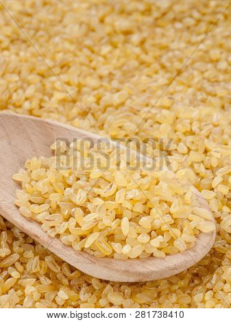 Bulgur In Wooden Spoon Close Up. Vertical With Copy Space
