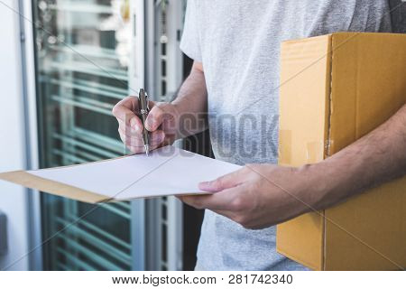 Delivery Mail Man Giving Parcel Box To Recipient And Signature Form, Young Owner Signing Receipt Of 