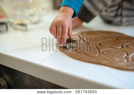 Closeup Of Toddler Child Making Cookies Pressing Heart Shaped Form In To A Spread Dough.