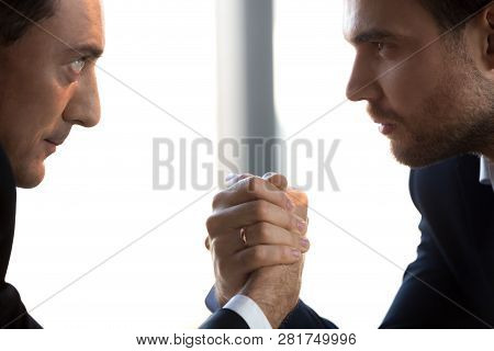 Two Confident Businessmen Compete Arm Wrestling Looking In Eyes, Closeup