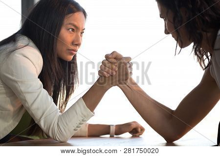 Young Asian And Caucasian Businesswomen Armwrestling Struggle For Leadership