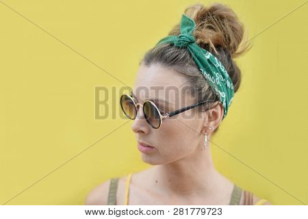 Portrait of stylish young woman in sunglasses outdoors on yellow background