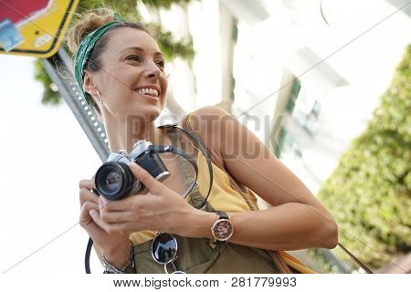 Stylish young woman with vintage camera in urban setting