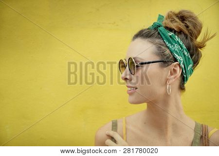 Portrait of stylish young woman in sunglasses outdoors on yellow background