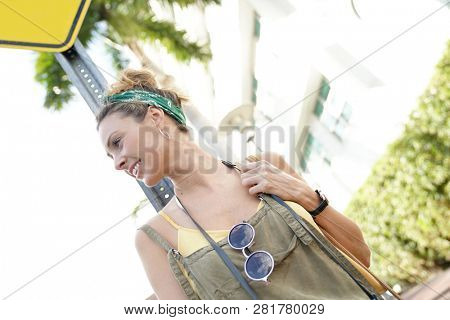 Stylish young woman posing and smiling in urban setting