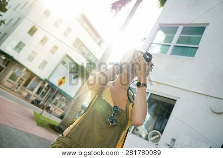 Stylish young woman taking photos with vintage camera in urban setting