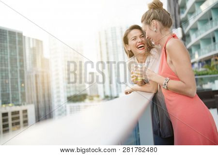 Two attractive funloving friends partying with drinks on rooftop bar in city