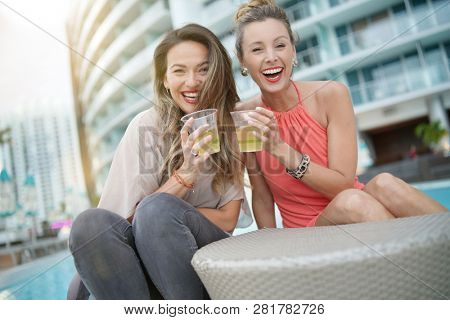 Two attractive funloving friends partying with drinks on rooftop bar in city