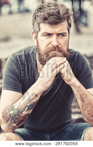 Man With Beard And Mustache Sits Outdoor. Bearded Man On Serious Face Looks Sad And Troubled, Suffer