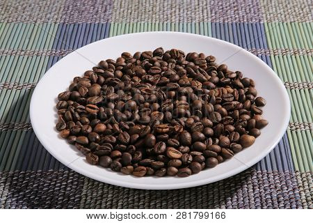 A Scattering Of Coffee Beans On A Plate. Bamboo Mat.