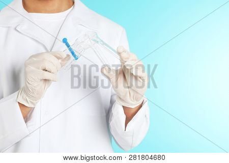 Male Doctor Holding Disposable Speculum On Color Background, Closeup With Space For Text. Medical Ob