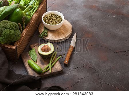 Assorted Green Toned Raw Organic Vegetables In Wooden Box On Dark Stone Background. Avocado, Cabbage