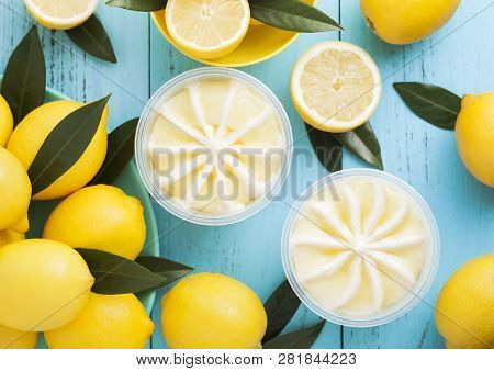 Plastic Jar With Lemon Cheesecake Mousse Dessert With Raw Lemons On Blue Wooden Background