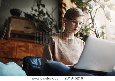Horizontalshot Of Creative And Stylish Urban Female Student In Glasses, Sitting On Crossed Feet And 