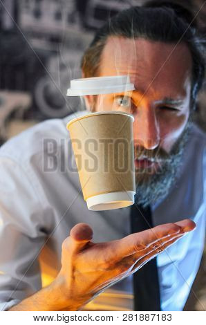 Levitating In The Air Paper Cup With Hot Coffee And Evaporation From It. Barista, A Bearded Young Ma