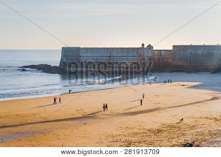 Fort In Torre Beach, Blue Sky And Ocean Waves, Yellow Brown Sand, People Walking In The Sand. Low Su