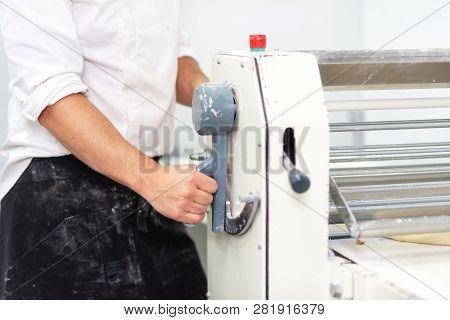 Baker Using Dough Sheeter Machine To Produce Croissants Dough At The Bakery .
