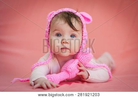 Cute And Adorable Six Months Old Baby Child Lying On Her Belly And Looking In The Camera With A Pink