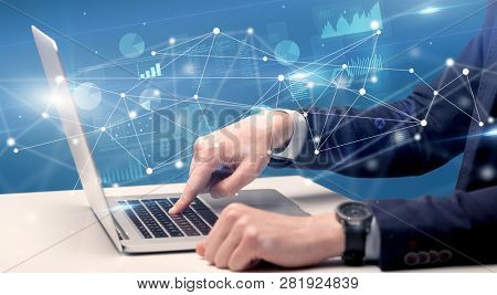 Businessman typing on laptop with linked reports charts grapghs around