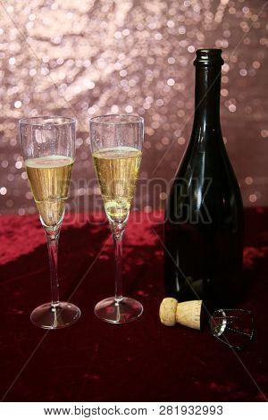 Valentines Day Champagne and Chocolates. Heart shaped velvet covered box of chocolates with roses and champagne with plastic champagne glasses. Room for text. 
