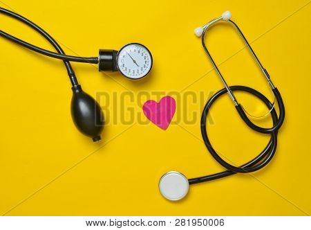 Cardiological Concept. Medical Monometer, Stethoscope, Decorative Heart On A Yellow Background. Top 