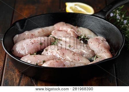 Raw Chicken Breast Mini Fillets In Rastic Cast Iron Skillet, Frying Pan With Herbs And Sea Salt