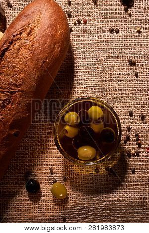 Fresh Bread Baguette With Olive Oil, Olives. Cheese And Rosemary On Wooden Background. Teasty Breakf