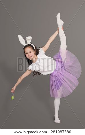 Gymnastics And Flexibility. Flexible Little Girl In Bunny Ears Doing Vertical Spli, Dancing On Gray 