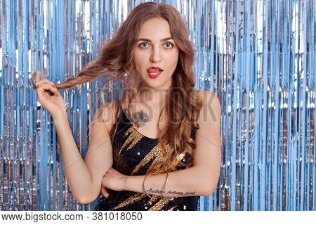 Adorable Cocky Woman With Beautiful Long Hair And Red Lipstick, Touching Her Curl And Showing Her To
