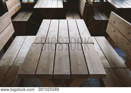 Empty Wooden Tables And Benches At Deserted Beergarden Outdoor Restaurant- Off Season Or Economy Cri