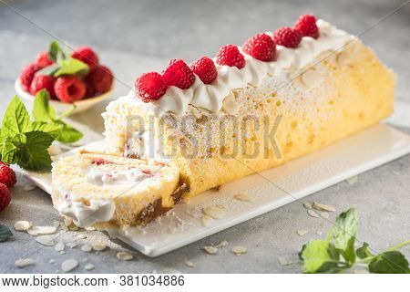Sponge Cake Roll Filling Cream And Raspberries, On White Stone Background. Soft Focus. Summer Food C