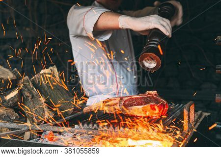 Cooking Steak In A Stone Oven. Chef Pepper The Steak On Fire.